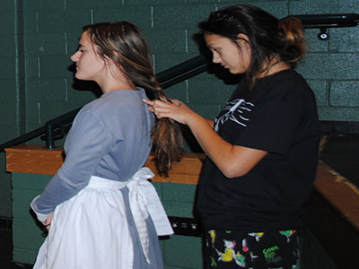 S*T*A*G*E crew member Maria Mills (right) braids actress Eliana Hubackers (left) hair during rehearsal.
