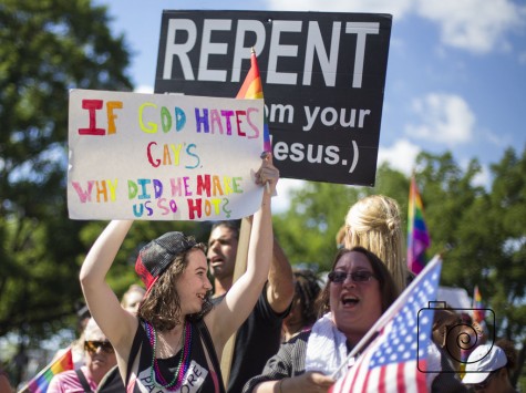 Gay pride parade attendees show their support for the cause by countering a religious, anti-gay sign with a poster of their own. 
