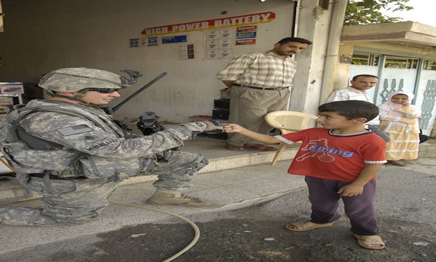 U.S. Army Staff Sgt. Aaron McFarland, from 1st Battalion, 8th Infantry Regiment, bumps knuckles with an Iraqi boy while he provides security during a market assessment at the Cherry Market in Al Karama, Mosul, Iraq on Sep. 17, 2008. (U.S. Army photo by Pfc. Sarah De Boise/Released)
