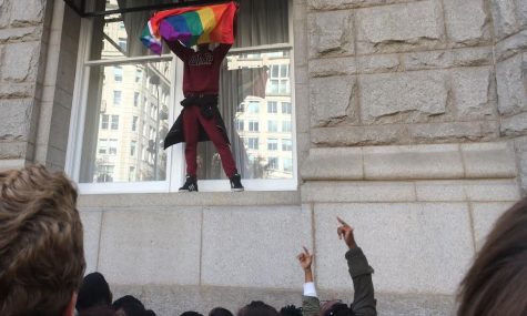 Another student waves a rainbow flag from a Trump Hotel window to the cheers of the protesters. Photo by Yael Hanadari-Levy.