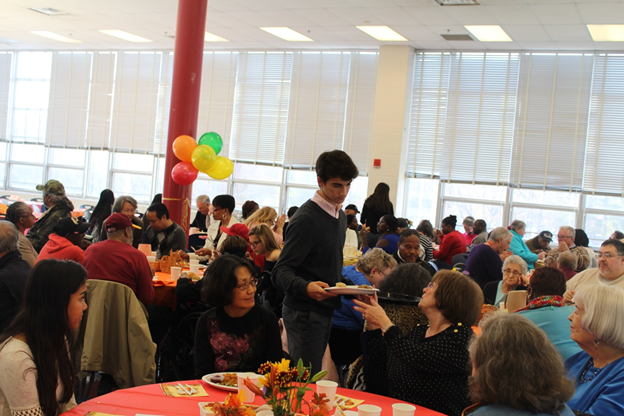 Senior Nick Bournias delivers a plate of food to a senior citizen, as junior Emilia Toloza enjoys a casual exchange with the table. Photo by Jack Linde 
