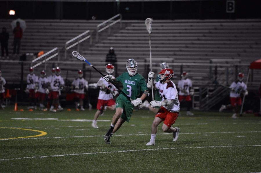 Junior Ethan Opdahl keeps the ball away from a Blair defender.  Although the team has struggled, Opdahl has been a bright spot, helping to keep the Wildcats competitive.  Already a captain as a junior, Opdahl supplies guidance for younger players both on and off the field.  He is defensive stalwart for the ‘Cats, and has already committed to play Division 1 lacrosse for the Bucknell University.  The season has certainly had its ups and downs.  The team has had exhilarating victories like an 11-10 win over Springbrook and some poor losses like an 18-2 blowout loss against Churchill High School.  But as long as Opdahl is anchoring the defense, the ‘Cats have a chance to win. Photo courtesy of Lifetouch Studios.