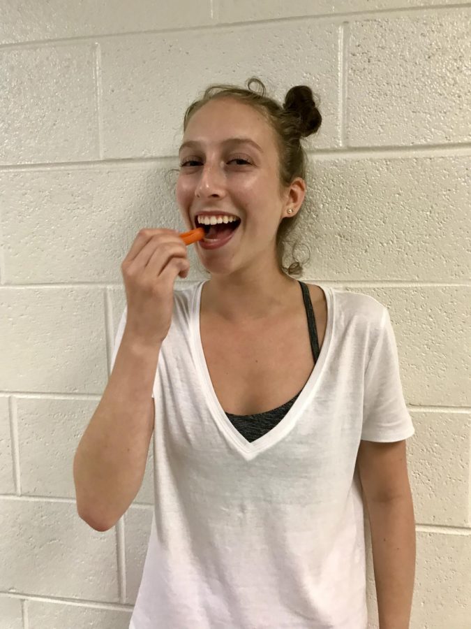 Senior Raya Seid smiles while snacking on some tasty carrots during lunch.  