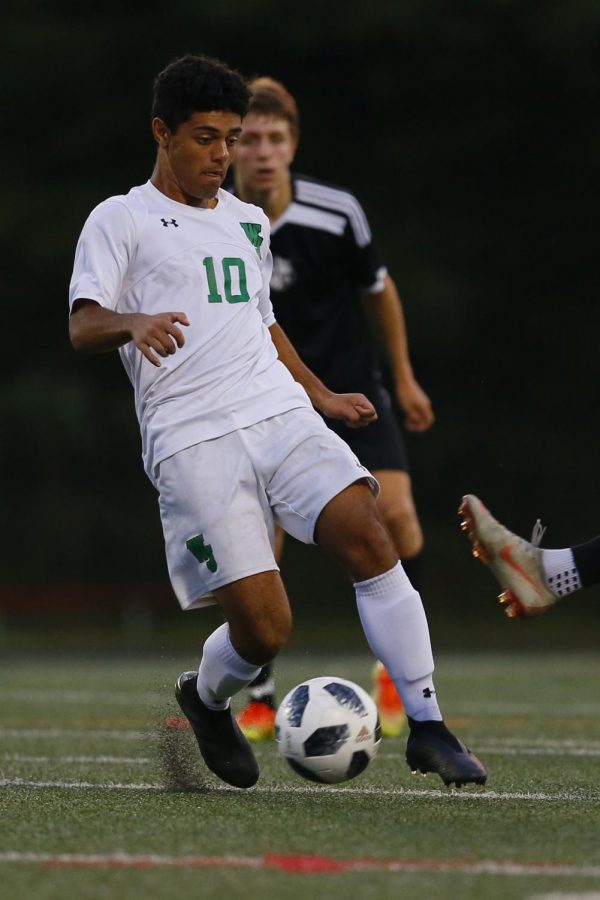 Senior midfielder Kamyab Salehi-Pirouz avoids the defender while turf pellets fly around his feet. Health concerns regarding the artificial turf have caused debate over its use on school fields.