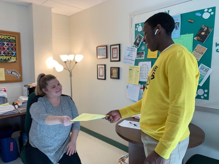 Senior DH Chris Manguelle hands a student transfer form to counselor Jamie Ahearn. Counselors try to help students new to WJ, but MCPS policy can make this difficult.