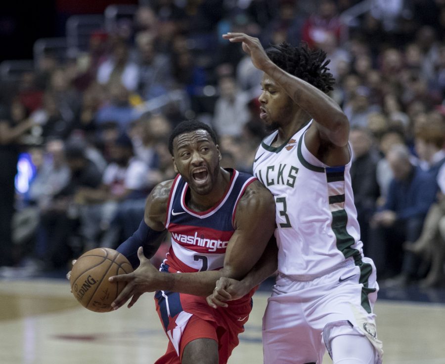 Wall (left) with the Wizards in 2018. The five time all-star drives into the lane for the layup. 