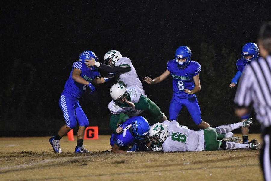 Senior Aidan Williams dives for a loose ball as a small fight emerges in the WJ-Churchill football game last November. WJs rivalry with Churchill extends beyond the athletic setting, as students from each school plagiarized the other schools stadiums.