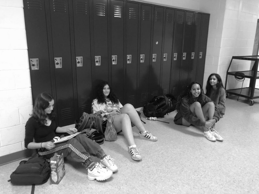 Junior Christine Vassel, freshman Sarah Lawerence, sophomores Jessica Vincent and Valeria Guillen talk and work on homework while waiting to get into their team room before practice.