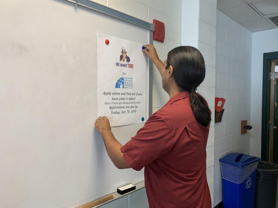 Social Studies teacher Oscar Ramos hangs a poster in his room. Given that it is his first year, decorating the walls makes him feel more settled in.