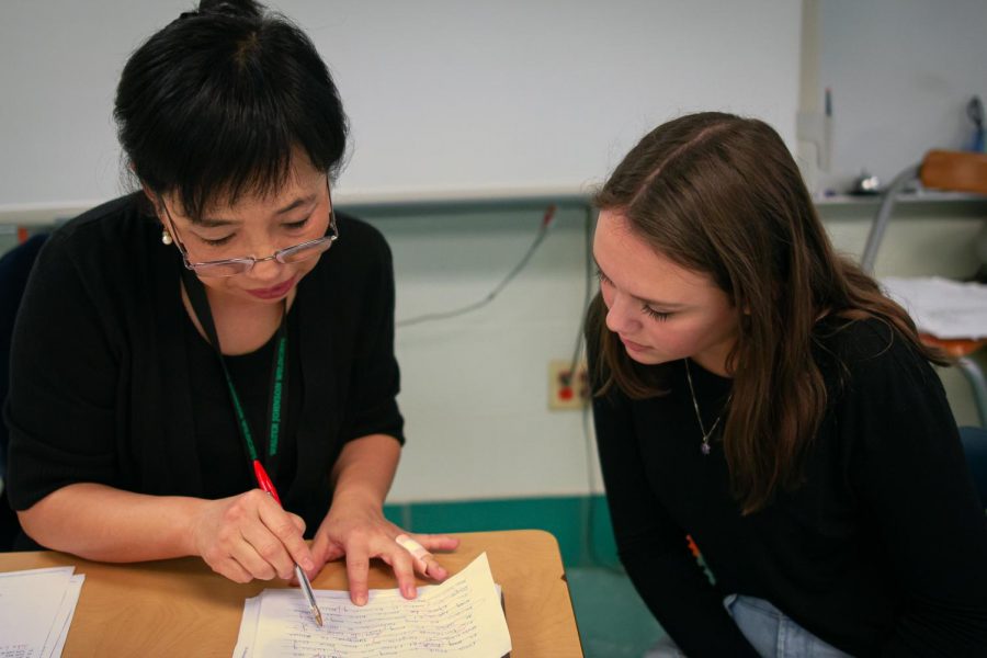 Xuhua Lucia Liang assists a student with their work during lunch. Students often come to Liangs classroom when they need help on a topic in Spanish.