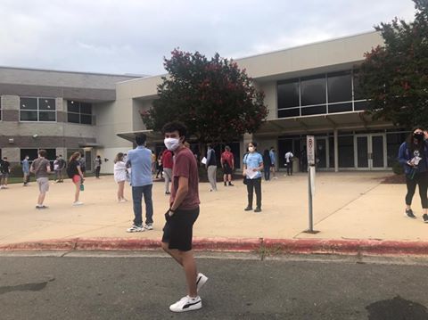 Senior Alex Finch stands outside of the SAT testing center in Durham, North Carolina. After observing the socially-distanced lines, face-covering masks, and diligent temperature checks, Finch described the setting as dystopian