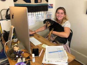 Psychology teacher Melanie Schwed poses with her puppy at her virtual “classroom.” Although her teaching is still quite similar to when it was in person, she misses being able to socially interact with students and co-workers. 
