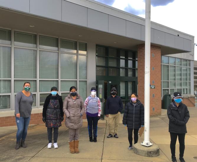 MCPS food workers stationed at Walter Johnson line up for a photo, accompanied by distribution manager Stephanie Atwood (far left). Though their responsibilities have changed since the regular school year, they are still committed to delivering meals to students.