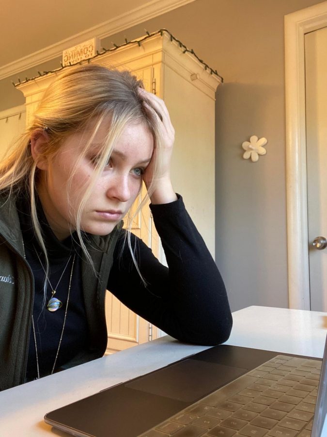 Senior Courtney Schnieder stares vacantly at a Zoom class on her computer screen. In addition to an external internship, Schnieder grapples with senioritis, causing her to lose connections to her high school classes.