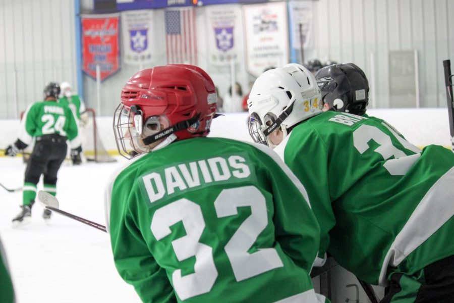 Captain Justin Davids looks onto the ice while his team is warming up. He gears up for another game with the Icecats while resting first on the bench.