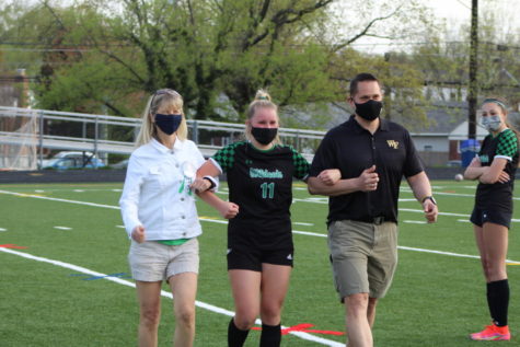 In typical senior night fashion, senior Courtney Schneider and her parents walk to greet the coaching staff and Principal Jennifer Baker.