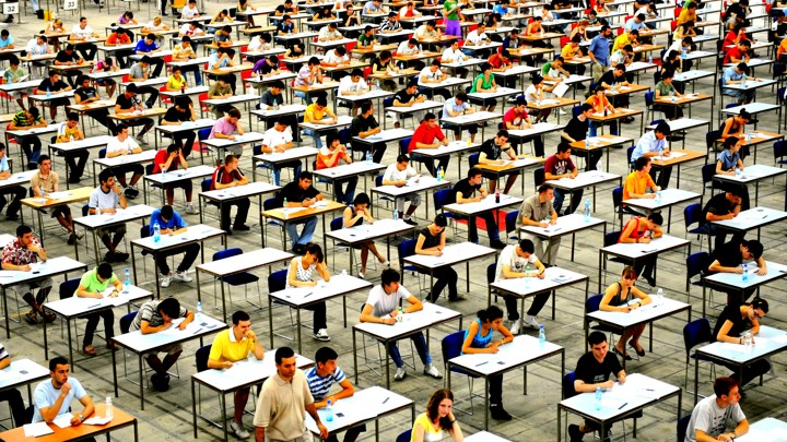 Students crowd into mass test taking halls to participate in standardized testing.