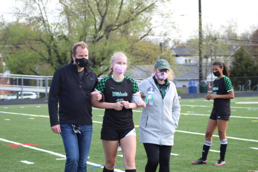 Senior Abby Matson walks elbow-in-elbow with her parents.