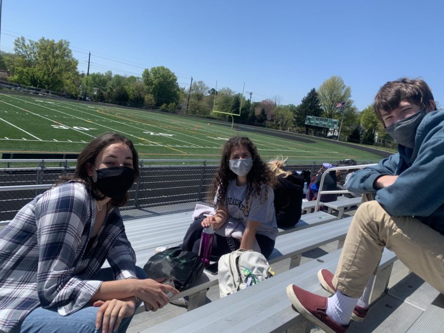 Students Olivia Herman, Sabrina Levri and Phillip Papadopulos sit outside on the bleachers during lunch. The bleachers are one of the options for places to sit during lunch. Students are expecting to sit six feet apart from one another on spots designated with tape.