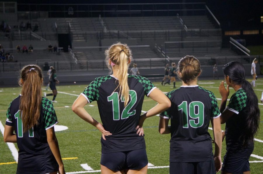 From left to right: Senior captain Emma Kothari, junior Caroline Williams, sophomore Adena Nielson, freshman Maya Panicker are looking out onto the field as their teammates prevent a scoring opportunity. They are eagerly waiting their return to the field after a short break.