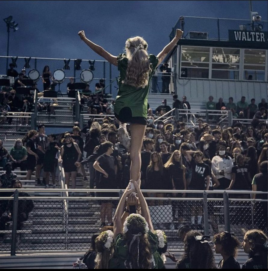 Junior Ava Franke pumps up the crowd during our homecoming game. Franke is a flyer for the team, striking a posed lib with one leg in the air.