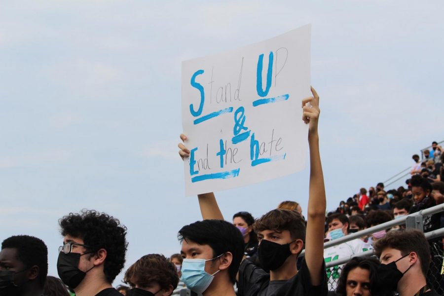 Junior Jack Melton holds up a poster that reads stand up and end the hate during the Stand Up to Hate walkout at WJ.