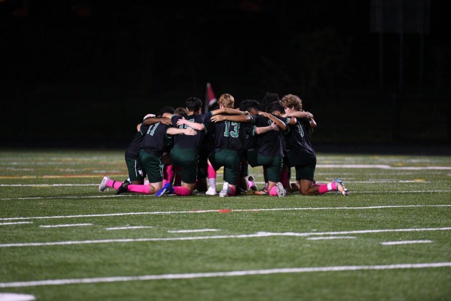 The starting lineup for the WJ boys varsity soccer team kneels in a huddle together before a regular season game against Churchill. This has become a ritual they do before every game.