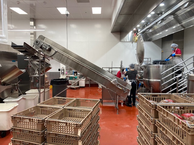 A massive metal shoot is hooked onto a production line to make for easy movement of lunch items to crates for easy transport. The MCPS food production facility houses industrial-grade equipment to make the massive quantities of food needed to feed MCPS students everyday.