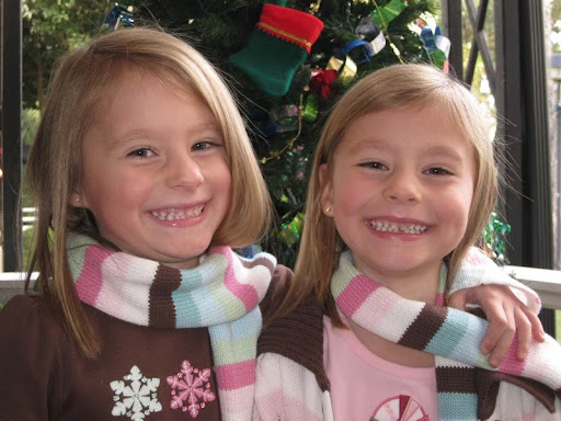 Twins Sofie and Isa Bernat at age seven smile eagerly as they wait in line to take a photo with Santa Claus in the mall. The sisters have been best friends since birth.