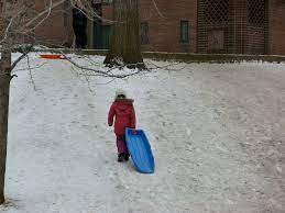 This girl carries her sled up a hill. It is likely a snow day, but if MCPS takes them away, we wont be able to go sledding.