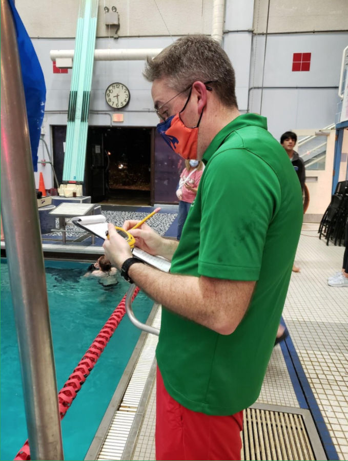 Grimes records swimmers’ times at the meet against Walt Whitman HS on Dec. 11. He is known for his uplifting attitude toward his team. “Before your swim [at the meets], he’ll prepare you for your race and tell you what you need to do,” swim team captain senior Graham Rogers said. “He’ll cheer loudly during your swim and congratulate you when you’re done.”