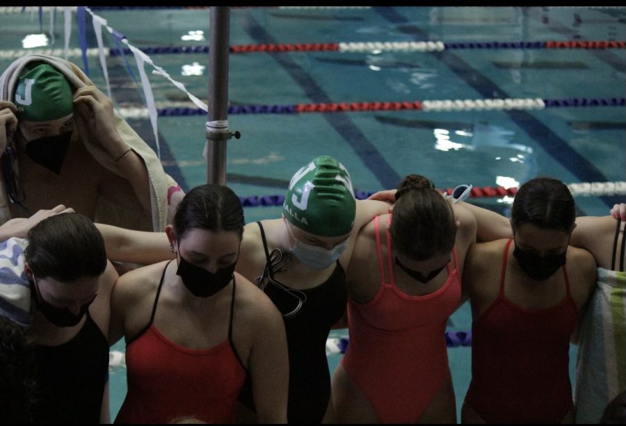 From left: junior Sienna Karp, senior Lianna Rosman, junior Grace Hudalla, senior Hanna Bingley and senior Hanna Juhasz wrap their arms around one another during a cheer. The Aquacats conduct a cheer before they begin swimming to help hype them up and swim faster.