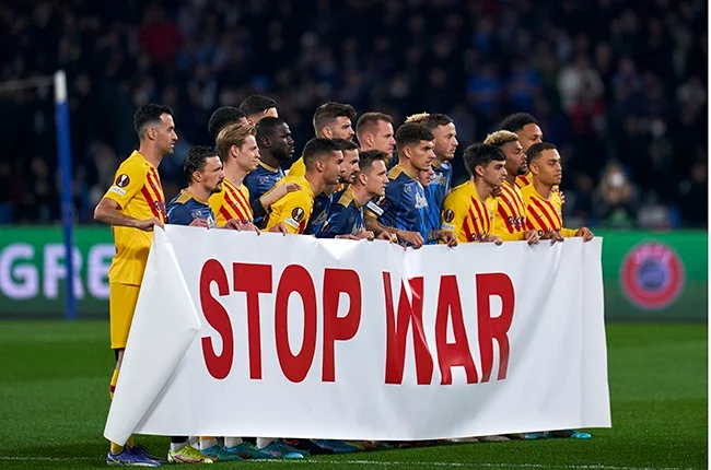 F.C. Barcelona and S.S.C. Napoli, two of the biggest clubs in the world, pose together with a Stop War banner before participating in a Round of 32 Europa League game. This is part of an effort by UEFA, one of the largest football organizations, to mobilize efforts to stand against aggression by Russia.