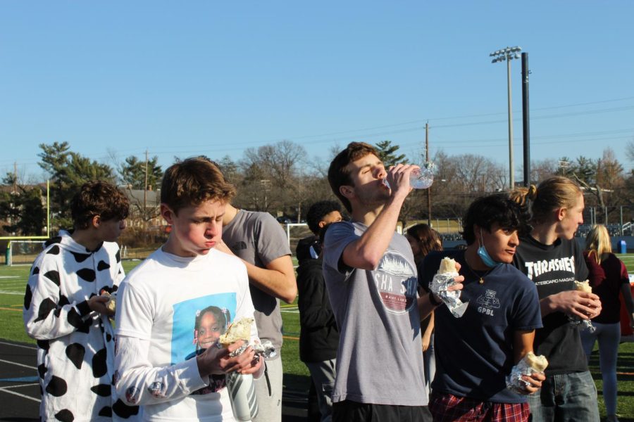 Senior Andrew Schell swallowing his burritos with water to get to the running part of the race. The track star, Schell has a winning streak for the Pennies for Patients Burrito Mile event, and won this year with a 7:15 mile time.