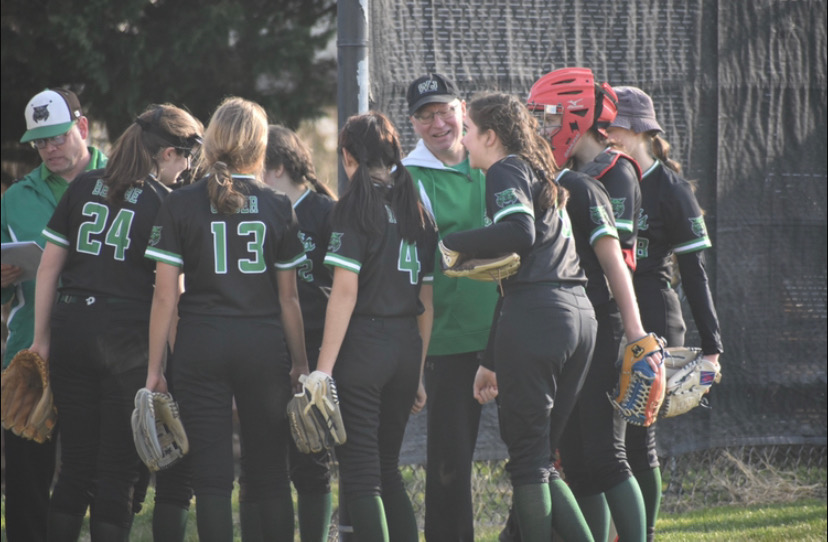 The WJ softball team huddles together during one of their first games. The team is looking to defend their regional championship from last season.