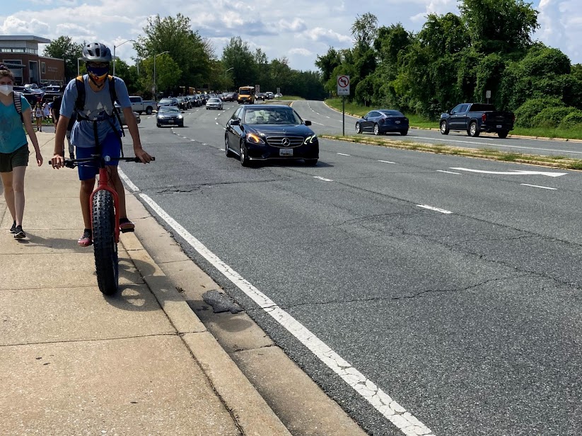 A student on a bike rides on the sidewalk, dangerously close to traffic on Rock Spring Drive. Dangerous unprotected sidewalks like this all across the county have led to numerous cyclist and pedestrian injuries and deaths.