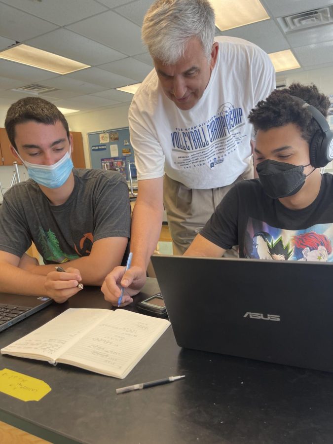 Physics teacher William Morris helps students look over their mistakes in their calculations for one of their assignments. He takes great care in assuring that students understand the basics of the subject.