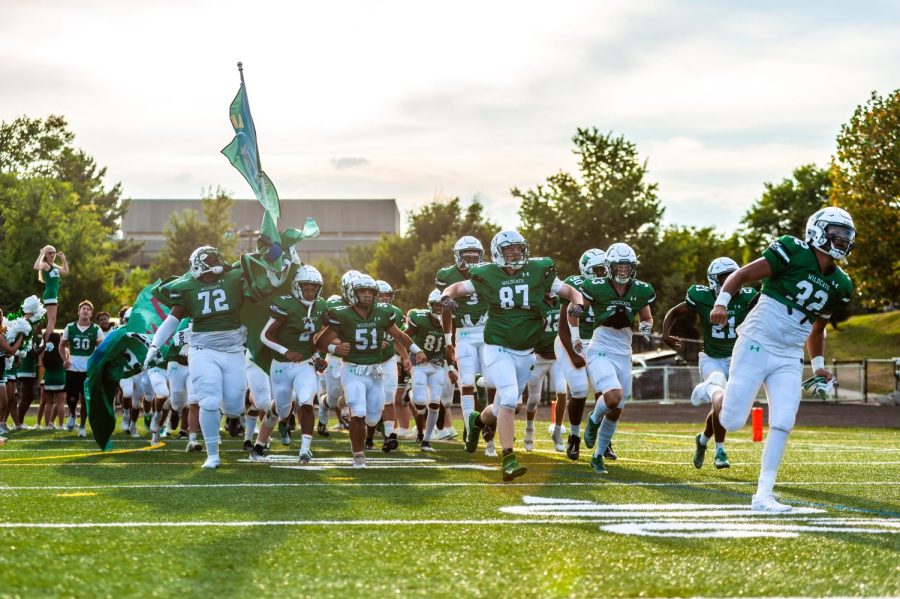 The football team runs onto the field to start the first game of the season. The crowd was dressed in green and cheered in support. Running out was exciting and nerve-racking. Everyone was feeling a ton of emotions, senior Elijah Barringtine said.