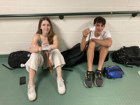 Freshman Travis Schultz and Charlotte Austegard display their IDs during lunch. As an increased security measure, administration has asked students to wear IDs while they are at school.