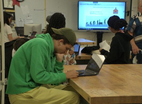 During period 6 of Foundations of Technology, sophomore Robin Dolle looks at his phone, while listening to music as Mr. Martin teaches his class. As many students seem uninterested in Tech class, this leads to questions whether Tech should continue be a required credit or if the cirriculum should be altered.