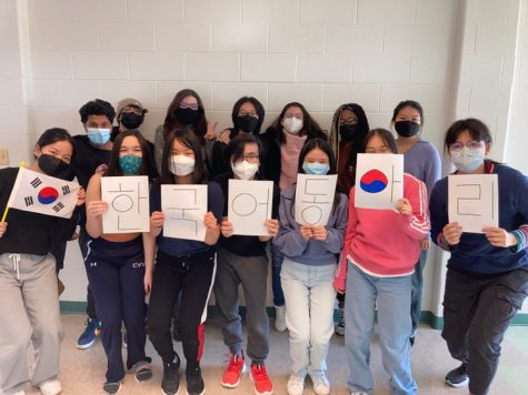Members hold up Korean letter signs that translate to Korean Language Club in English.