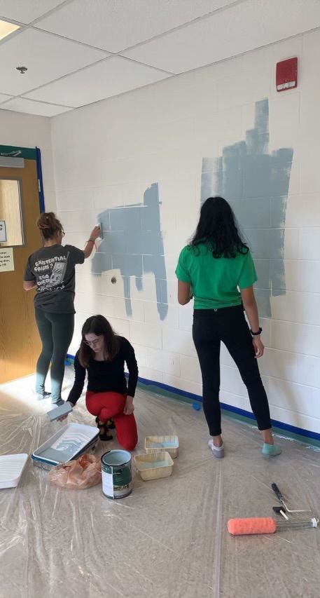 Co-treasure Kathleen Winters (far left), president Norah Mannle (center) and secretary Niya Tripathi (far right) paint the walls of the new Wellness Center.