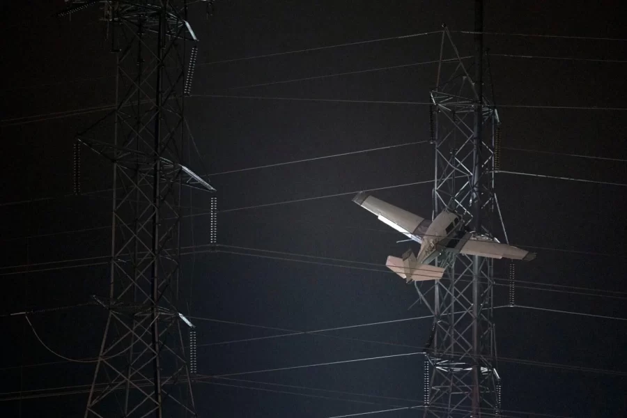 The plane hangs carefully within the power lines. Thousands of locals experienced outages.