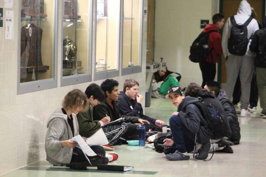 A group of friends sit together outside the gym during lunch. Eating in the hallways provides much more freedom in deciding what kind of spot to eat in.