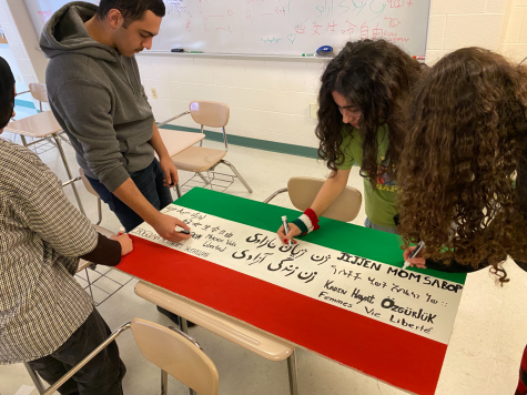 Members of the Middle Eastern North African (MENA) club paint a ceiling tile displaying the revolutions motto, Women, Life, Freedom written in different languages.