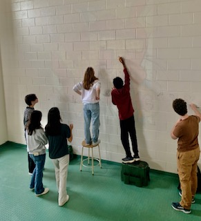 The Art Honor Society plans out their next hallway mural. It showcases WJ in large colorful bubble letters.