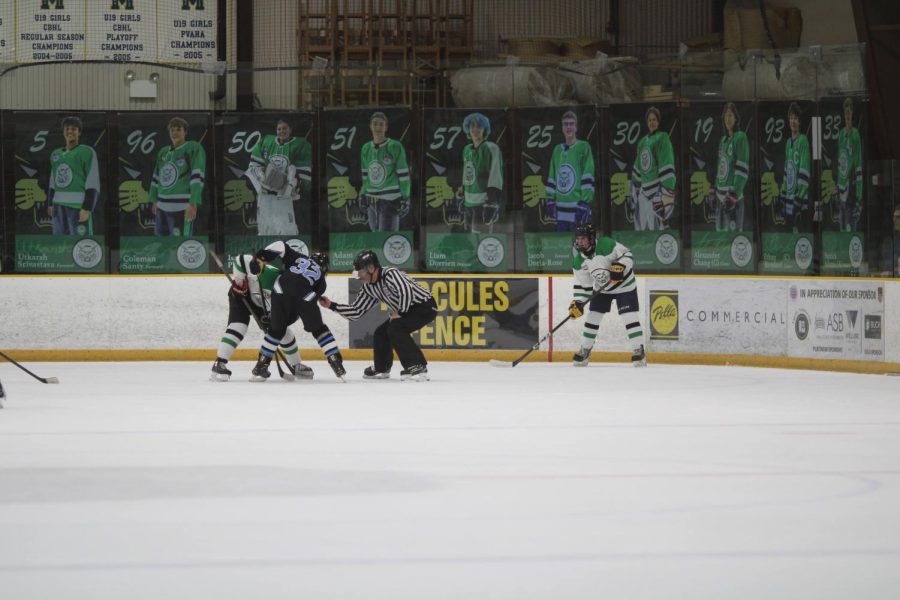 The Icecats line up for a faceoff in their defensive zone against Whitman. The banners picturing all of the senior Icecats are hanging behind the glass for their senior night.