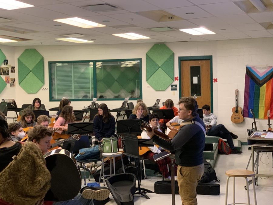 Morris plays the guitar while instructing her class of Guitar 1 students. Leading a class where each student plays individually requires different teaching methods and techniques than one where the class plays as an ensemble.