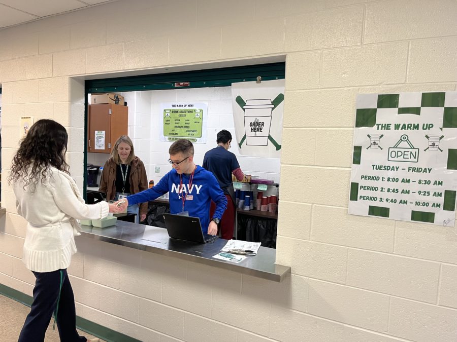 A student worker at The Warm Up gives a customer, Psychology teacher Nicole McCarn, her change after purchasing a coffee. His favorite part of working at The Warm Up is taking orders.