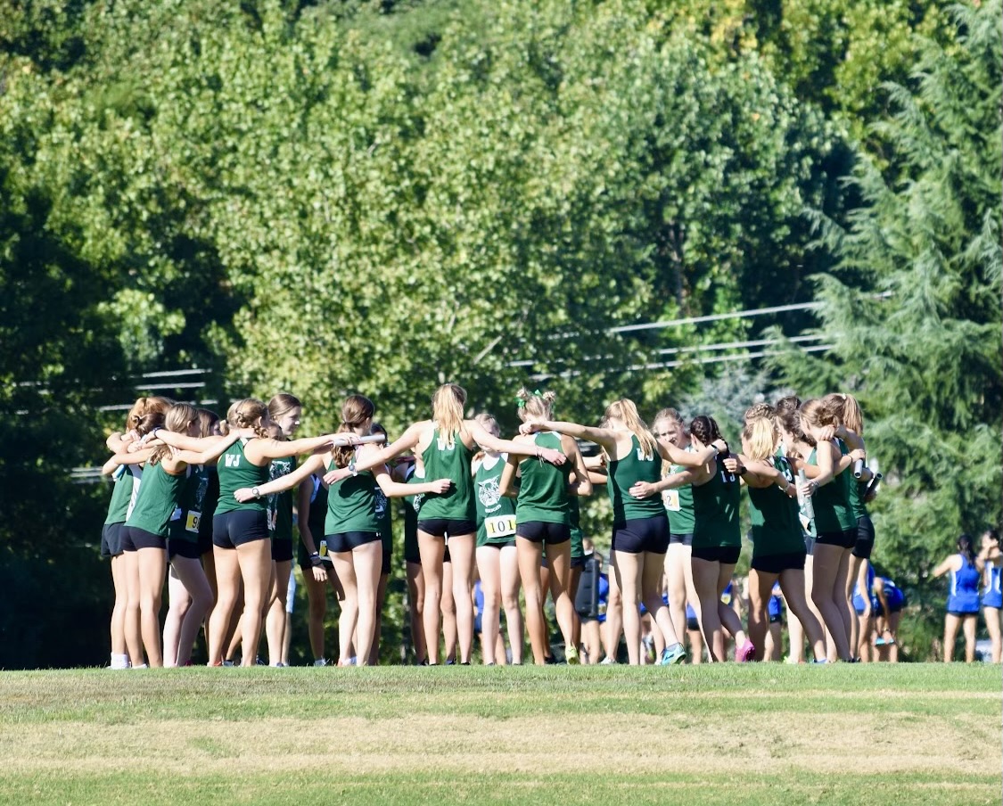 The girls cross country team comes together in a huddle before their relay race begins. The first meet of the season was at Woodward Relays, where the runners were in pairs and ran a combined six miles.